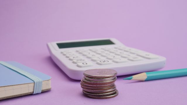 A calculator, a stack of coins and a pencil.