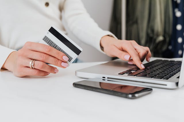Person using a laptop and holding a credit card